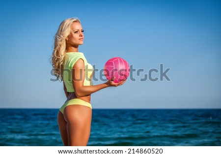 Beach woman in bikini holding a volleyball