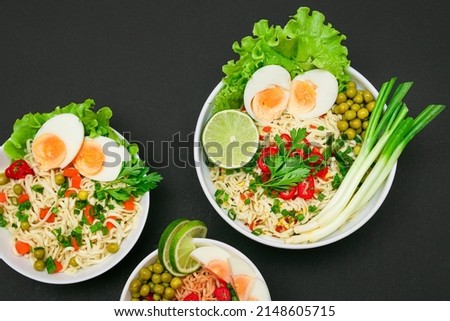 Beautiful Noodle Dish with Green Onions, Eggs, Green Pea, Red Hot Pepper, Greens and Lime on Sushi Mat. Instant Noodles with Vegetables