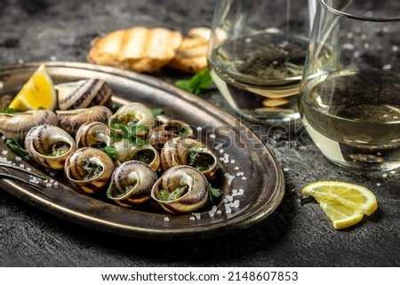Baked snails with butter and spice on dark background. Snails baked with sauce, Bourgogne Escargot Snails. gourmet food. concept of french cuisine, Long banner format. top view. Royalty-Free Stock Photo #2148607853