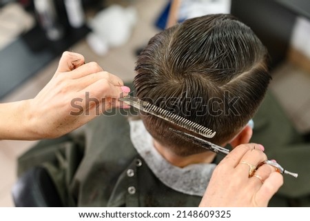 Teen guy gets a haircut during a pandemic in a barbershop, haircut and drying hair after a haircut, haircut with scissors. Royalty-Free Stock Photo #2148609325