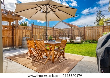 Cute craftsman bungalow cottage front door with rocking chairs backyard fenced with patio furniture and umbrella Royalty-Free Stock Photo #2148620679