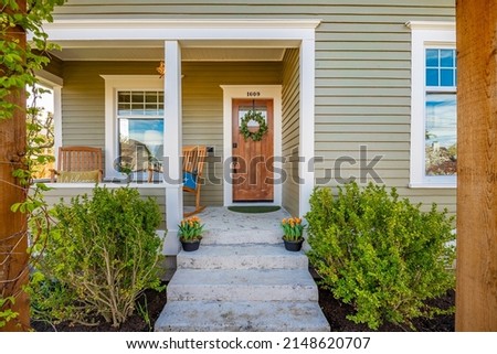 Cute craftsman bungalow cottage front door with rocking chairs backyard fenced with patio furniture and umbrella