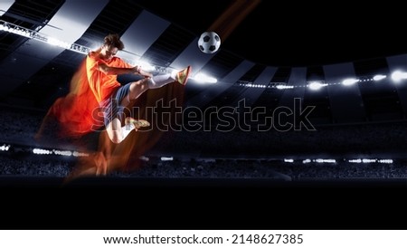 Attack. Professional football or soccer player in action on night stadium with flashlights, kicking ball for winning goal. Concept of sport, competition, motion, overcoming. Field presence effect.