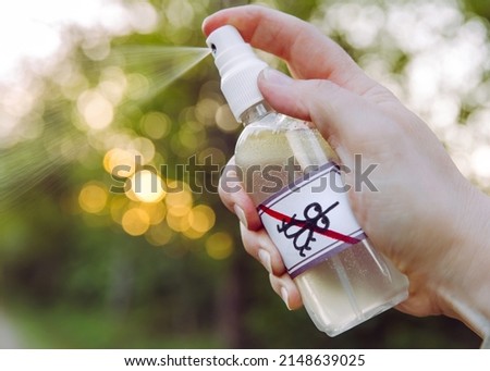 Close up view of woman hand holding and using DIY homemade essential oil based mosquito repellent outdoors in forest in the evening. Royalty-Free Stock Photo #2148639025
