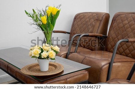 Bouquet of flowers on the table in the interior with leather chairs, office space decor.
