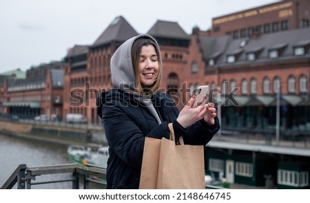 Happy young woman with smartphone and package, shopping concept, online shopping.