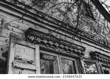 View of an old uninhabited house. The peeling brick walls are painted white. Shutters with a pattern. Wood cutting. Provence style. Vintage style. Black and white.