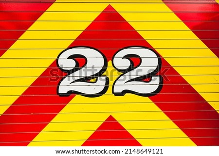 White painted number twenty two outlined in black on bright red and yellow chevron pattern fire truck detail