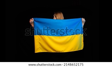 Beautiful Ukrainian girl with the national state flag of Ukraine on black background. Copy space. Russian Ukrainian War. Help and Pray for Ukraine. Stop war.