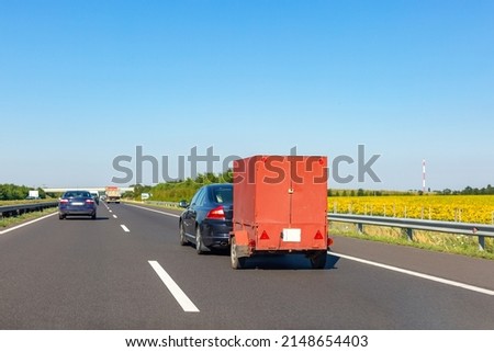Black car with red carry-on cargo trailer on the highway Royalty-Free Stock Photo #2148654403