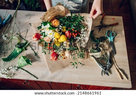Top view of a woman florist hands making a bouquet while working in a flower shop. Making a bouquet of mixed unusual original flowers. Fresh flowers bouquet arrangement. Royalty-Free Stock Photo #2148661961