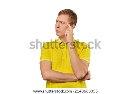 Thoughtful guy in yellow T-shirt looking to left isolated on white background. Pensive young man thinking, guy putting hand to his head and looking to left, philosophical reflection concept