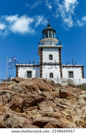 Old lighthouse with Greece flag on blue sky background