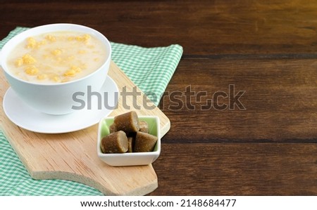 Traditional Colombian food called mazamorra,based on cooked corn dissolved in milk,accompanied with panela in pieces (sweet from sugar cane). Dark wooden background.