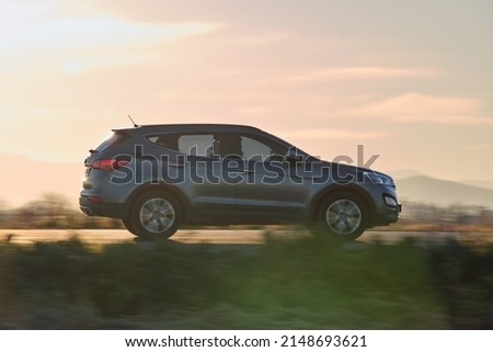 SUV car driving fast on intercity road at sunset. Highway traffic in evening Royalty-Free Stock Photo #2148693621