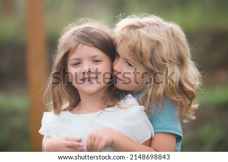 Two little children hug and kiss each other in summer garden. Kids couple in love. Friendship and childhood.
