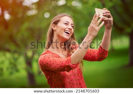 This will make a great profile pic. Shot of a young woman taking a selfie outside.