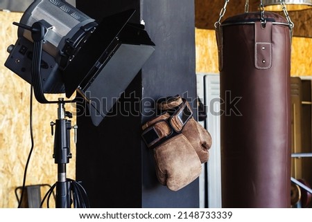 Fragment of a gym with a punching bag and boxing gloves in retro style. selective focus