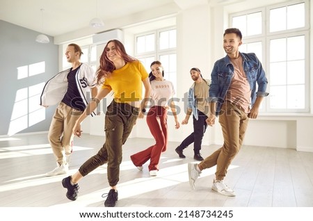 Group of happy beautiful young people enjoying a contemporary dancing class. Team of cheerful smiling dancers in casual wear practising a new choreo and having a good time together in a modern studio Royalty-Free Stock Photo #2148734245