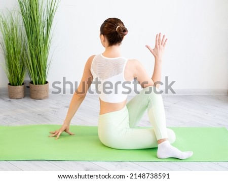 Yoga training. Home workout. Healthy wellbeing. Unrecognizable sportive woman in sport clothes practicing flexibility exercise indoors on mat at gym studio.