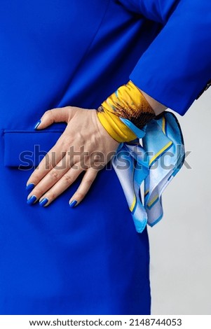 Female hand on a blue jacket with a blue manicure