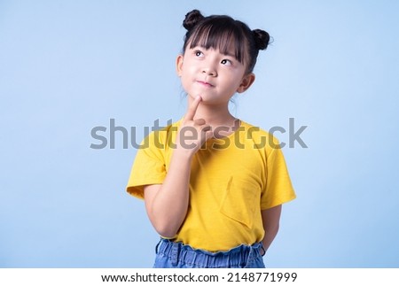 Image of Asian child posing on blue background Royalty-Free Stock Photo #2148771999