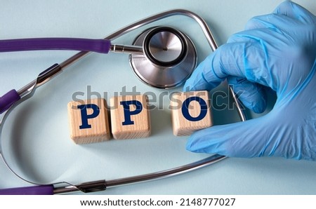 A hand in a medical glove puts cubes with the abbreviation PPO (Preferred Provider Organization) on the background of a stethoscope. Medical concept Royalty-Free Stock Photo #2148777027