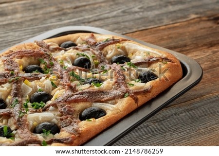 Pissaladière is the famous French onion pie. This onion "pizza" with anchovies and olives comes from Nice and can be made with bread or cooked dough. Royalty-Free Stock Photo #2148786259