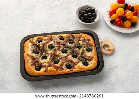 Pissaladière is the famous French onion pie. This onion "pizza" with anchovies and olives comes from Nice and can be made with bread or cooked dough. Royalty-Free Stock Photo #2148786261