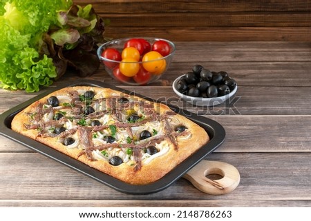 Pissaladière is the famous French onion pie. This onion "pizza" with anchovies and olives comes from Nice and can be made with bread or cooked dough. Royalty-Free Stock Photo #2148786263
