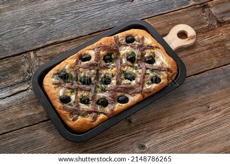 Pissaladière is the famous French onion pie. This onion "pizza" with anchovies and olives comes from Nice and can be made with bread or cooked dough. Royalty-Free Stock Photo #2148786265