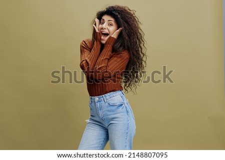 WOW OFFER. Excited beautiful curly female look at camera, touch cheek and say Wow. Copy space for fashion brands clothing, free place for your advertising. Studio shoot isolated green background