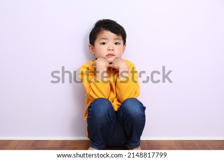 An Asian boy dressed in yellow. A picture of a boy who is not energetic.