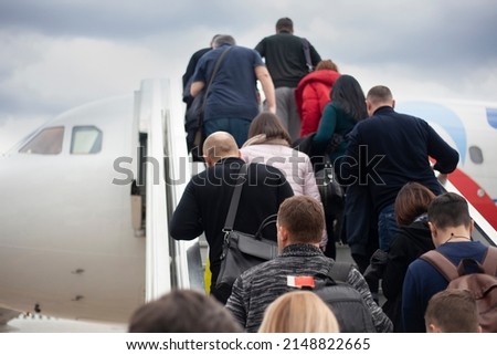 People climb the ramp to the plane. Passengers are loaded into the aircraft. People go up the stairs to the cabin of air transport. Event at the airport. Royalty-Free Stock Photo #2148822665