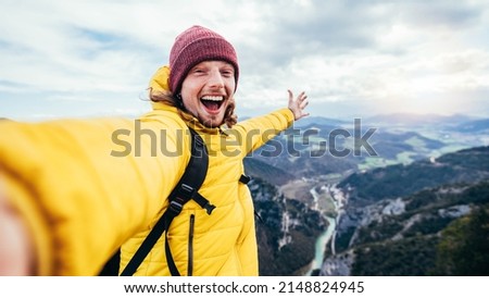 Young hiker man taking selfie portrait on the top of mountain - Happy guy smiling at camera - Hiking, sport, travel and technology concept