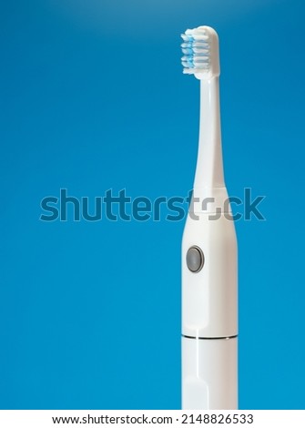 Electric ultrasonic toothbrush on blue background.