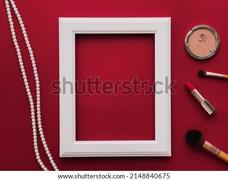 White vertical art frame mockup, make-up products and pearl jewellery on red background as flatlay design, artwork print or photo album concept