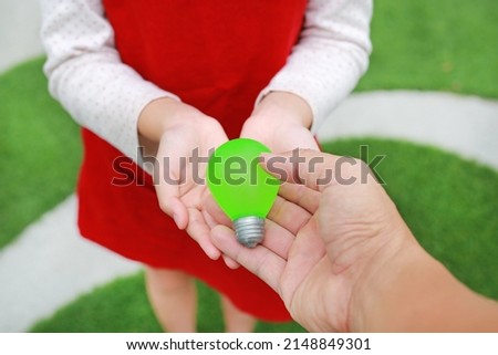 Closeup people hand giving a toy bulb for little girl child at the garden. Love the earth concept.