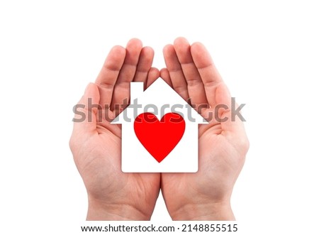 Paper house with red heart cutout in hands isolated on white background with clipping path. 