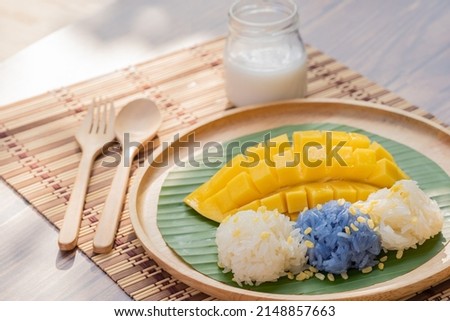Mango sticky rice is placed on a banana leaf in a wooden dish, Thai dessert. Royalty-Free Stock Photo #2148857663