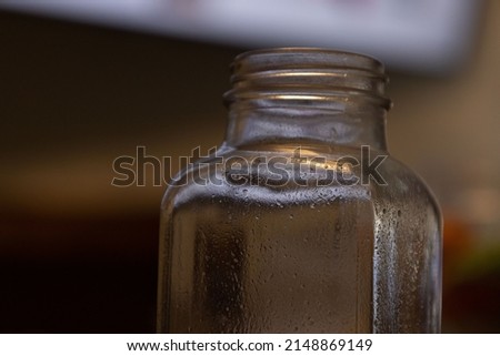Empty glass bottle with no lid sits in focus.