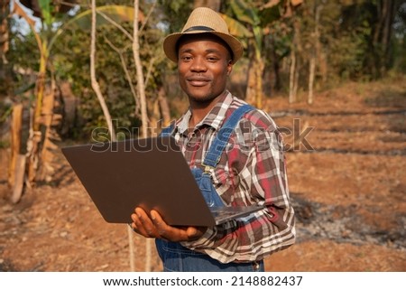 Portrait of a Young African farmer on his plantation with a laptop, technology in the agriculture concept Royalty-Free Stock Photo #2148882437