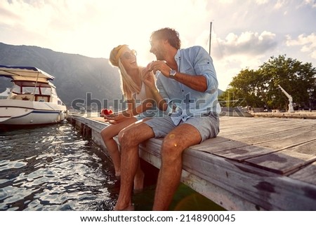 Lovely young couple sharing moments of bliss and eating watermelon sitting on wooden jetty by water. Togetherness, lifestyle, luxury concept. Royalty-Free Stock Photo #2148900045