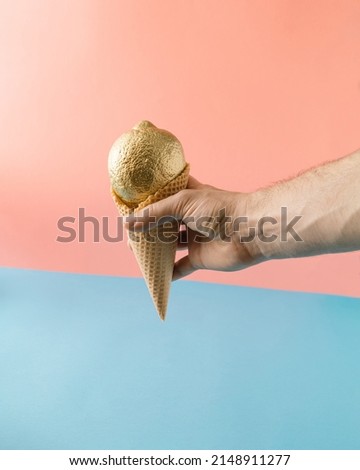 Summer furit concept with hand holding ice cream cone with golden lemon.On  pastel pink blue background.Minimal creative idea.
