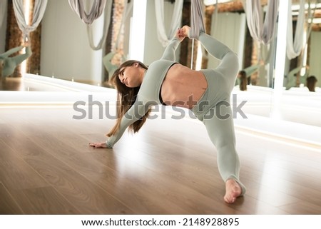 A young athletic woman does aerial yoga