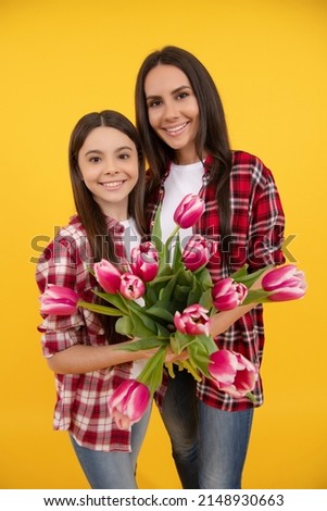 happy mother and daughter with tulip flowers on yellow background. selective focus