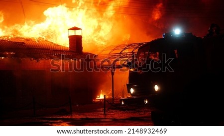 fire truck and flasher fire engine. fire on the roof of the house. a burning at building house . home insurance apartment concept. huge fire night blazes houses 911. property damage arson protection Royalty-Free Stock Photo #2148932469