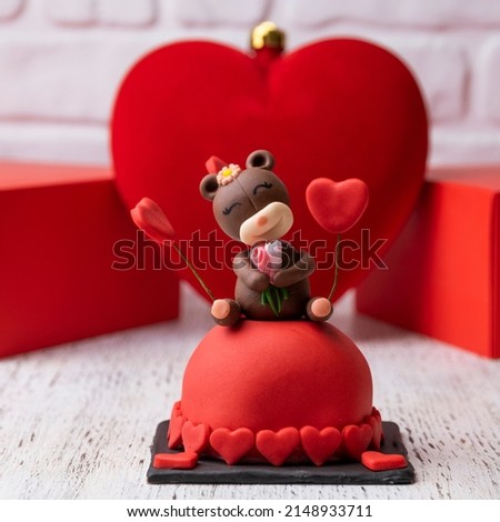 Delicious mourning cake. Birthday cake. Mini red round cake with teddy bear decorations. Background decorated with red heart and box.