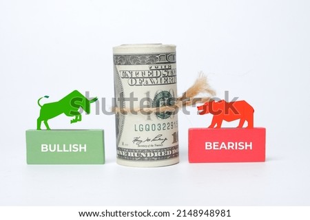 A picture of fake money with bullish and bearish market symbol at wooden block. Market trend concept.