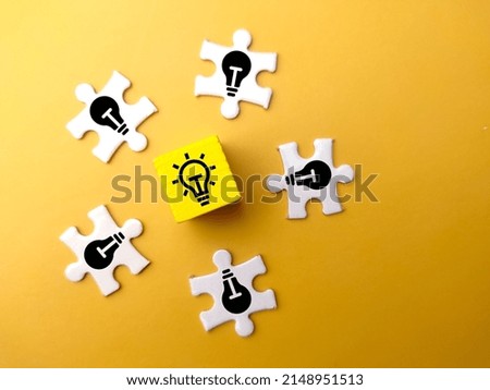 Colored cubes and white puzzle with light bulb icons on lit and dim bulbs.